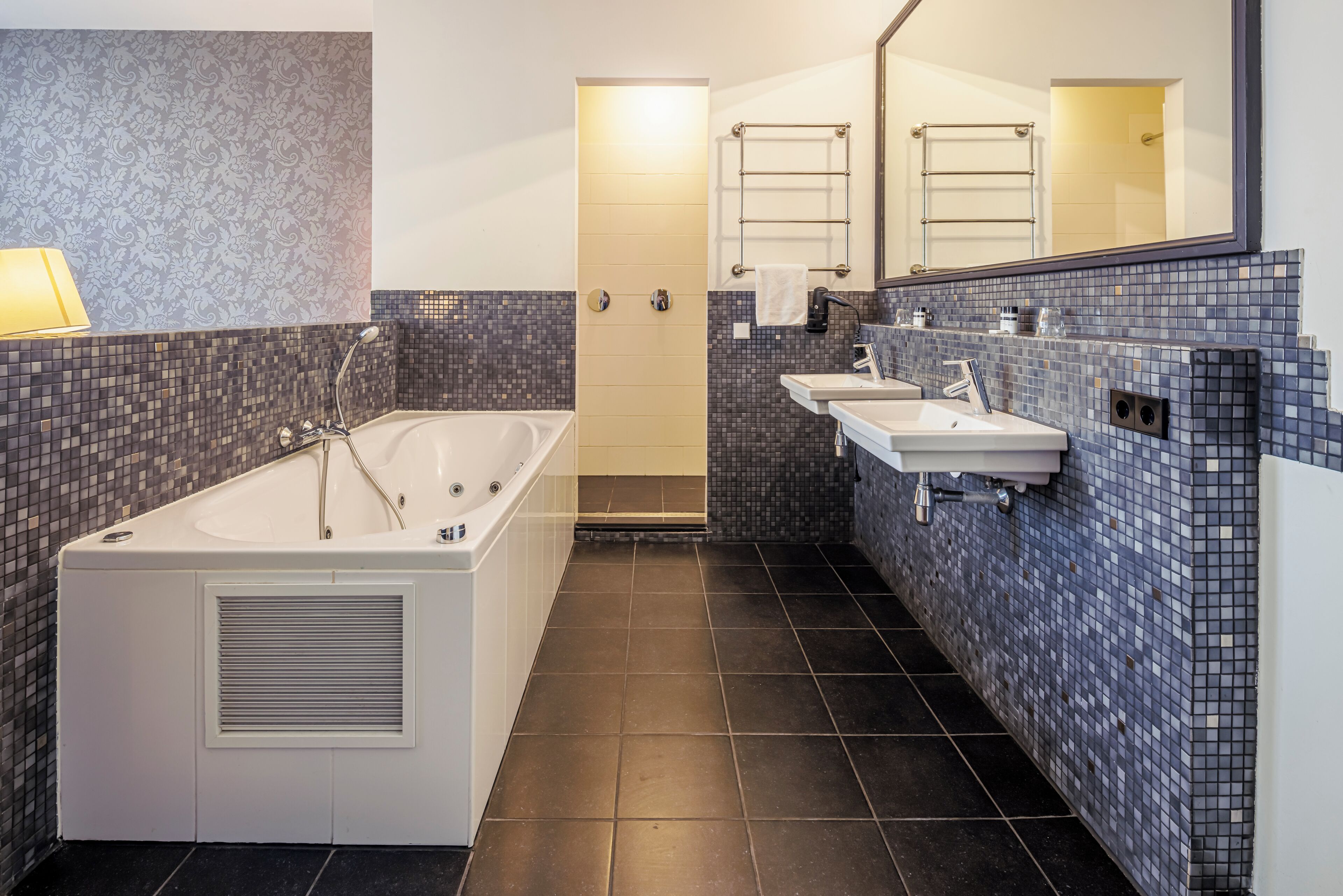 Un baño moderno con una bañera independiente, dos lavamanos y un espejo grande.