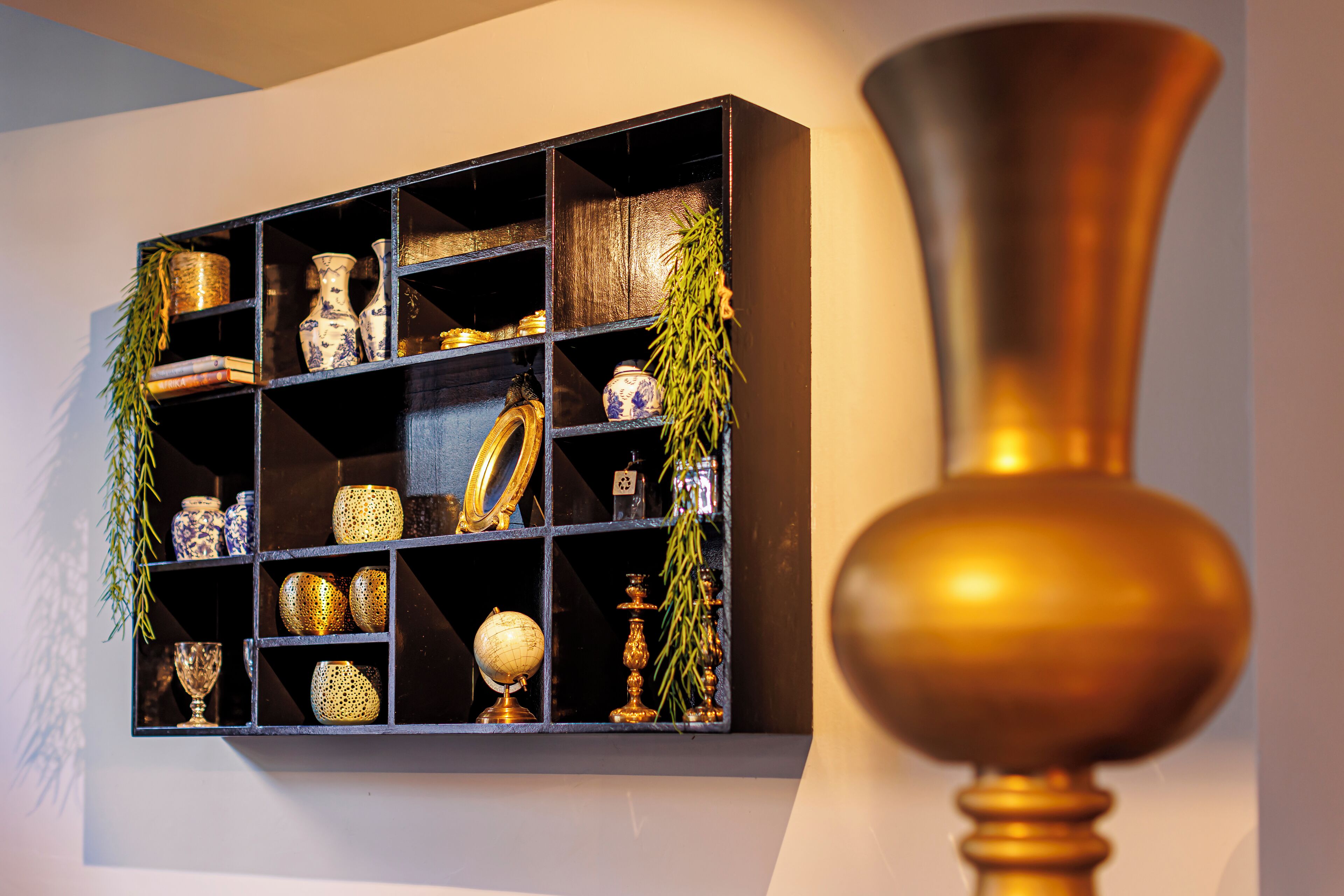 Une étagère ornée de divers objets décoratifs, notamment des vases, un globe terrestre et une plante suspendue.