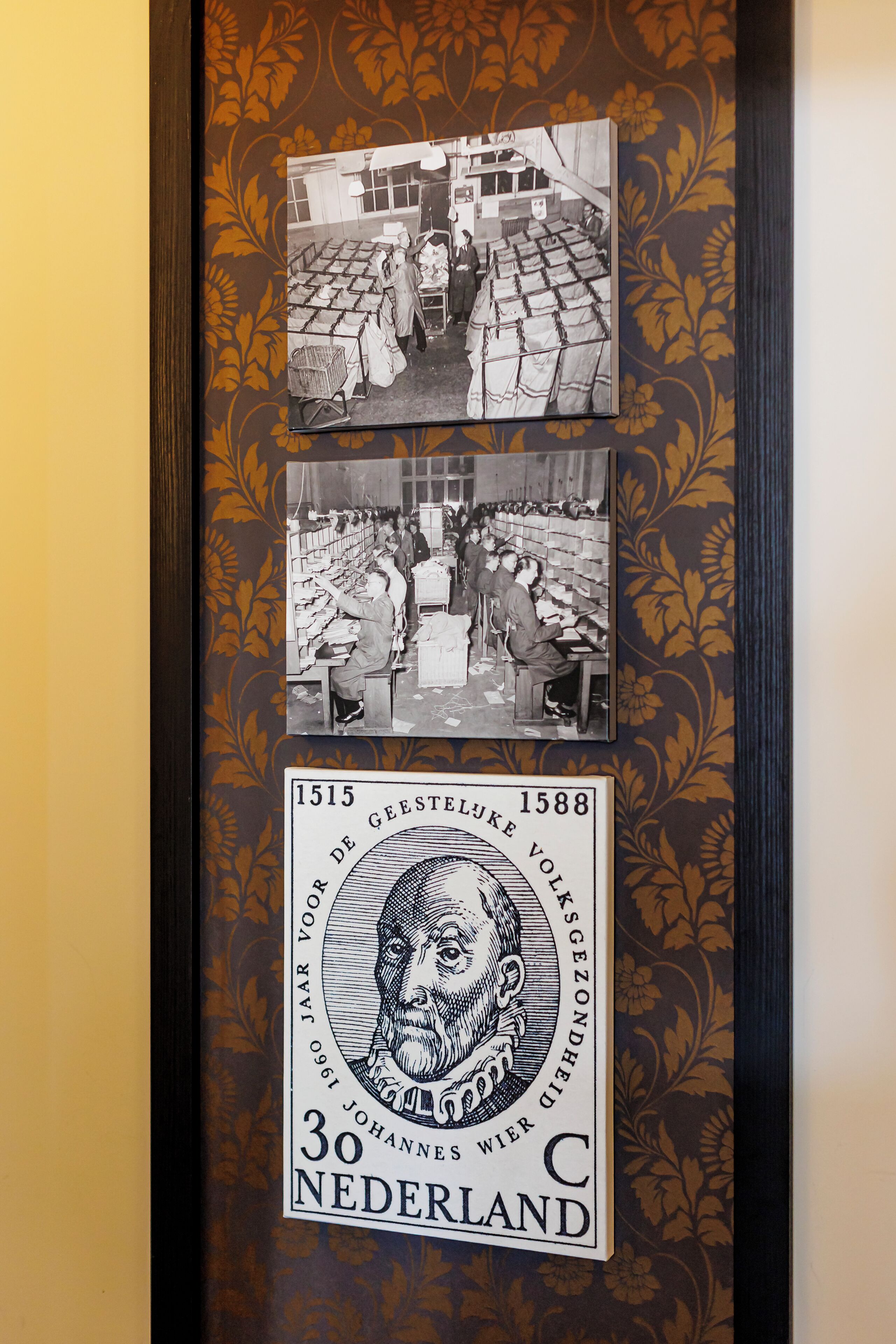 A framed historical photograph of a textile factory with workers and machinery, and a commemorative coin from 30 years of Gelderland.