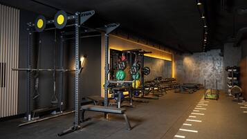 A gym with weightlifting equipment, benches, and a wall-mounted rack.