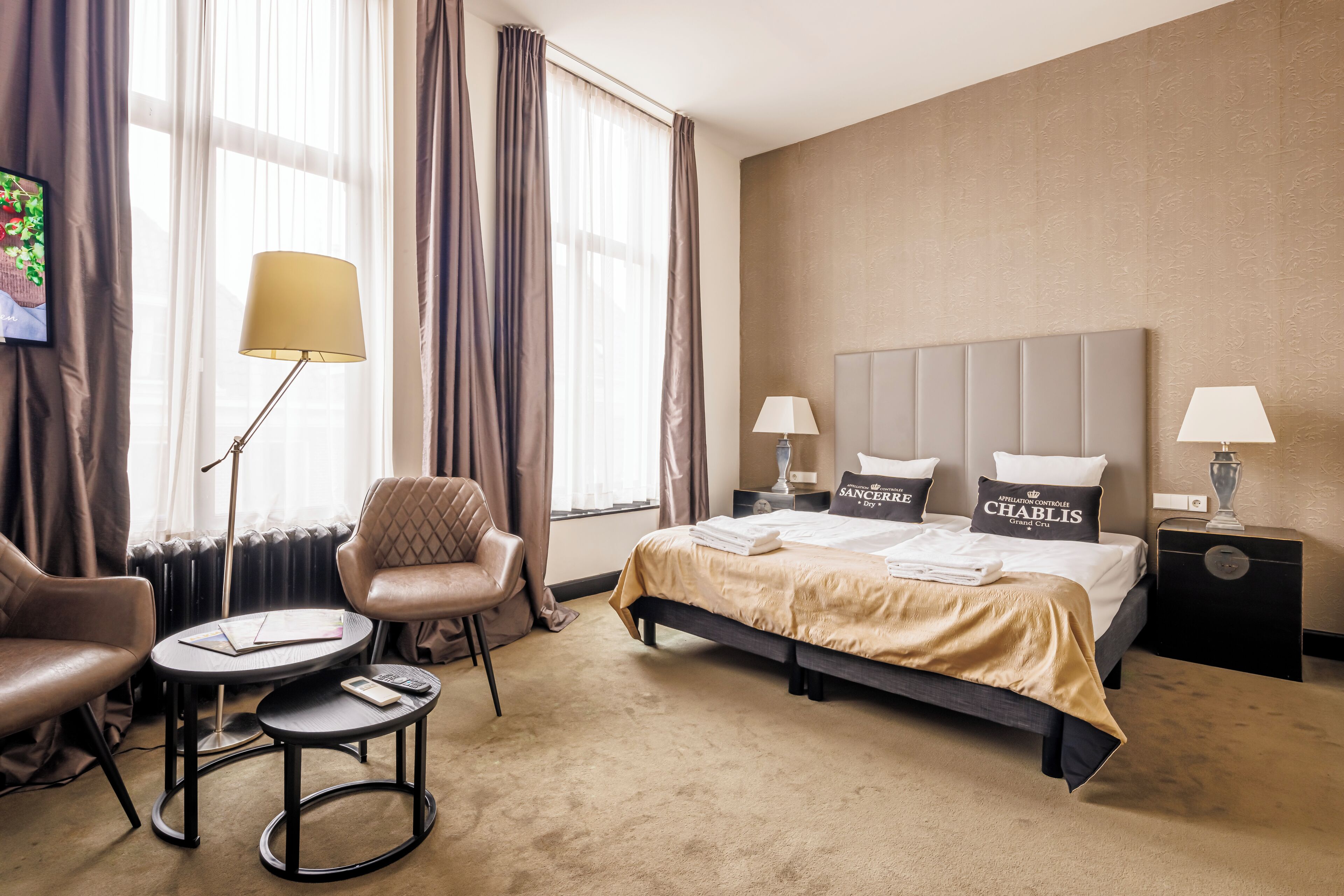 Ein Hotelzimmer mit einem Bett, zwei Stühlen, einem kleinen Tisch und einer Lampe.