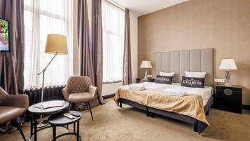 Ein Hotelzimmer mit einem Bett, zwei Stühlen, einem kleinen Tisch und einer Lampe.
