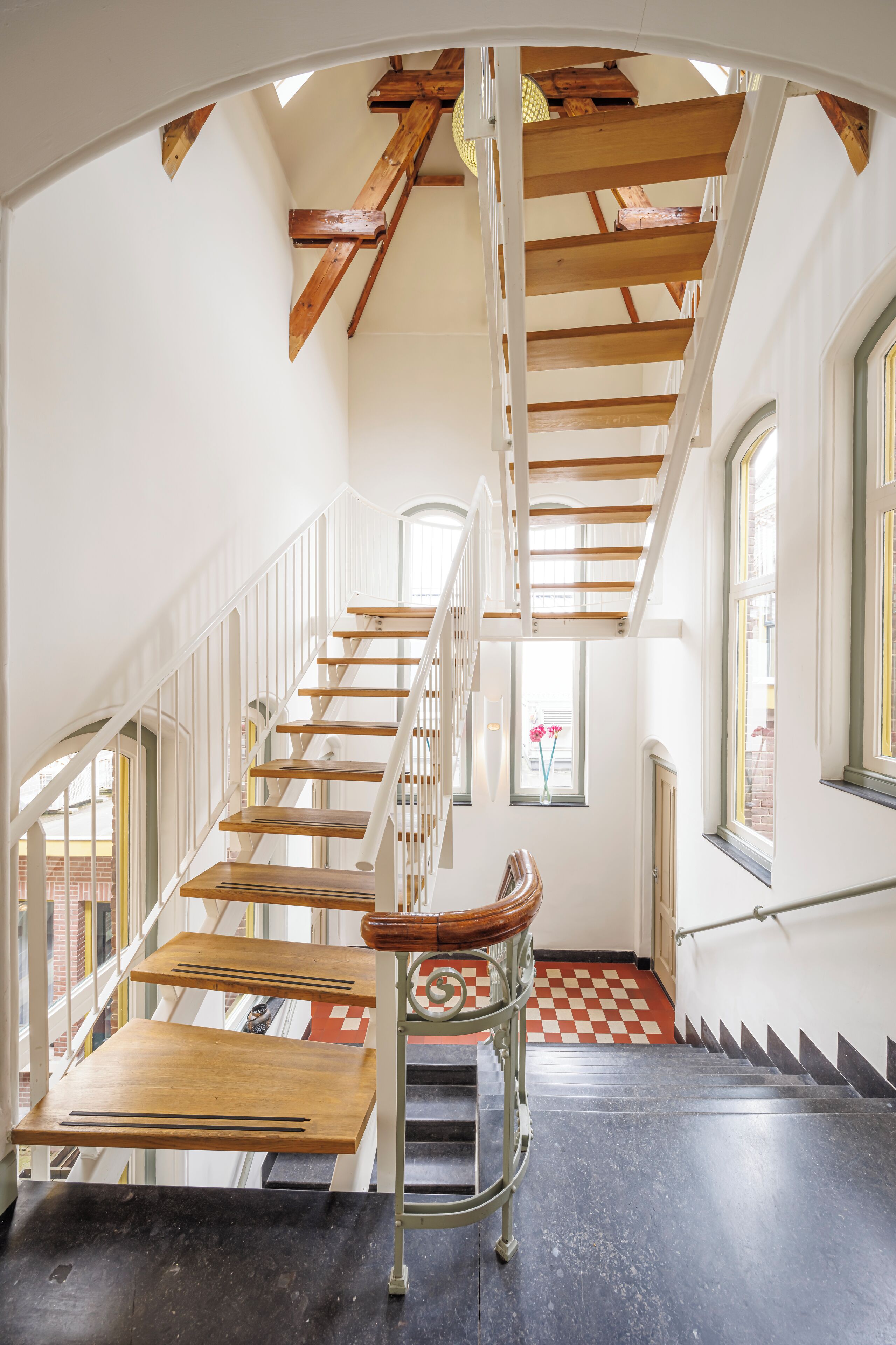 A staircase with wooden steps and white railings, leading to an upper floor.