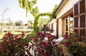 A patio area with a garden, outdoor furniture, and a building with large windows and shutters. - Aumallia Hotel & Spa (Felanitx)