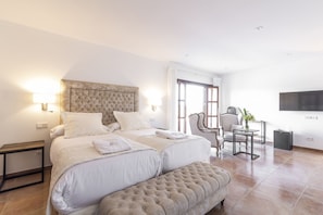 A hotel room with a large bed, a chair, a small table, and a TV on the wall. - Aumallia Hotel & Spa (Felanitx)