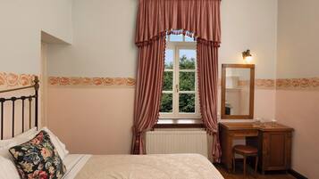Une chambre à coucher avec un lit, une fenêtre avec des rideaux, un bureau en bois avec une chaise et un miroir.