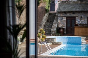Una piscina con muelle de madera, paredes de piedra y una escalera de piedra que lleva a una puerta.