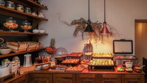 Un bufé con diferentes opciones de comida, una estación de café y una planta decorativa.