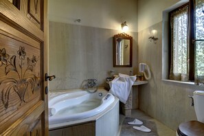 A bathroom with a wooden vanity, a bathtub, a toilet, and a window with curtains.