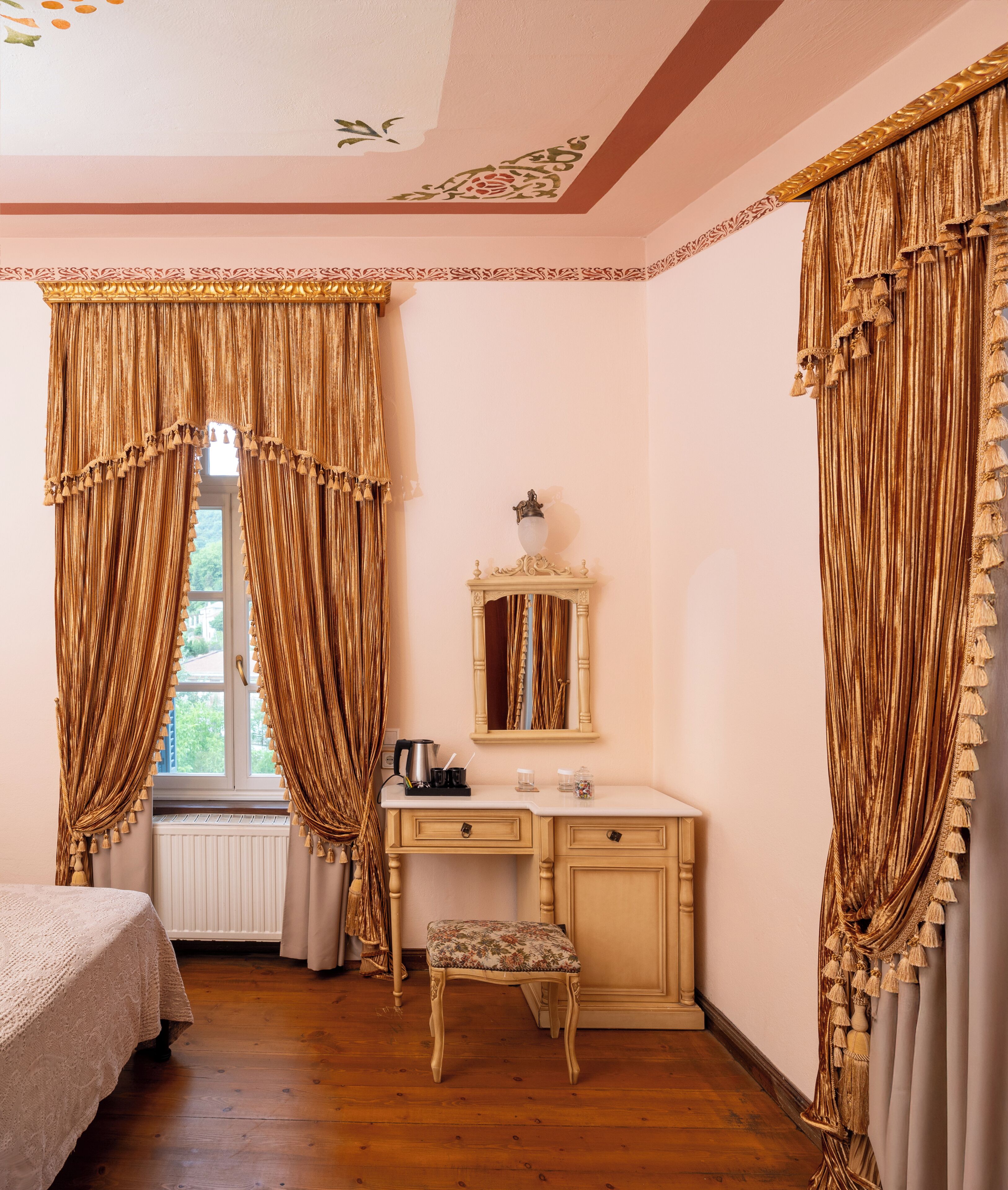 Un dormitorio con cama, cómoda, tocador con espejo y cortinas.
