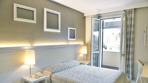 Habitación de hotel con cama, mesitas de noche, lámparas y vistas a través de una puerta.