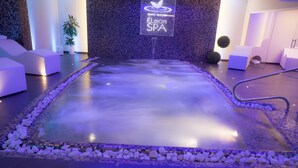 Un área de spa con suelo reflectante, asientos y un letrero que indica que es el 'Centro Benessere Élaion SPA'.