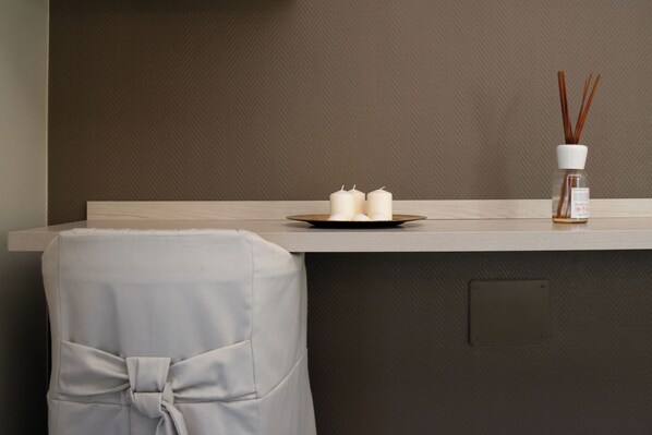 A modern room with a wooden counter, two candles, and a reed diffuser.