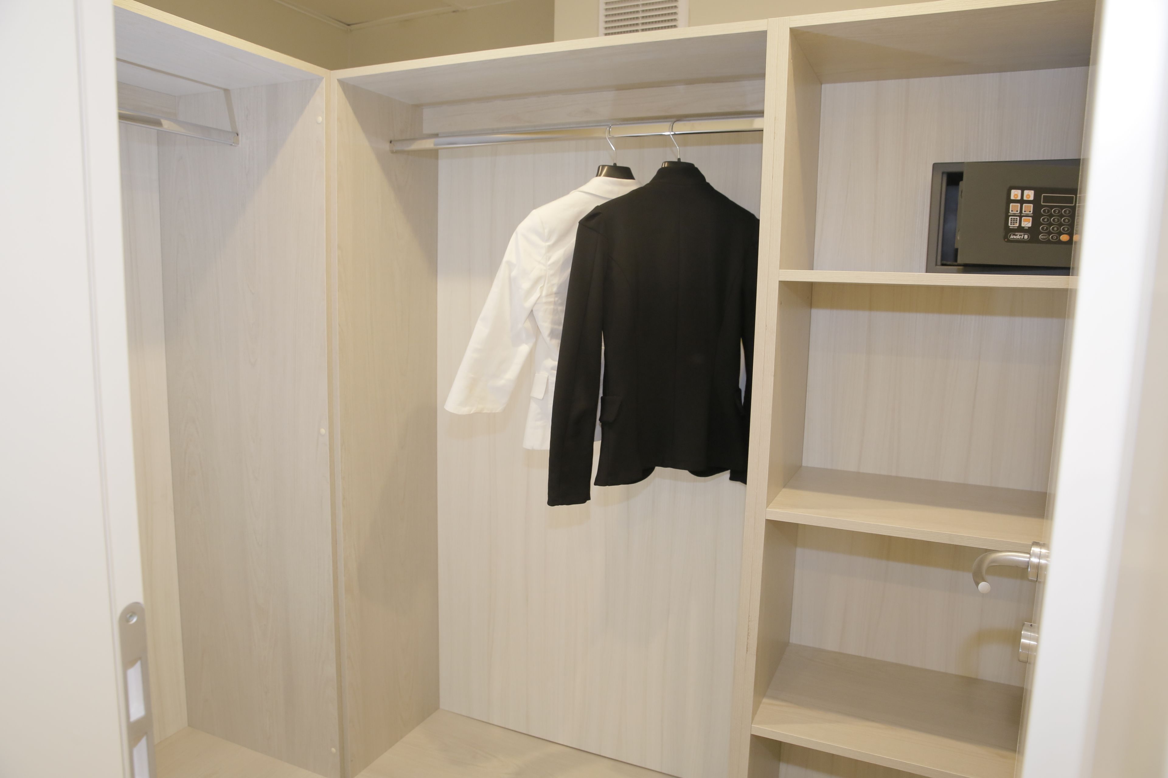 Un vestidor con paneles de madera, barra para colgar ropa y una caja fuerte empotrada.