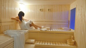 Una sala de sauna con bancos de madera, un cubo de madera y una ventana.