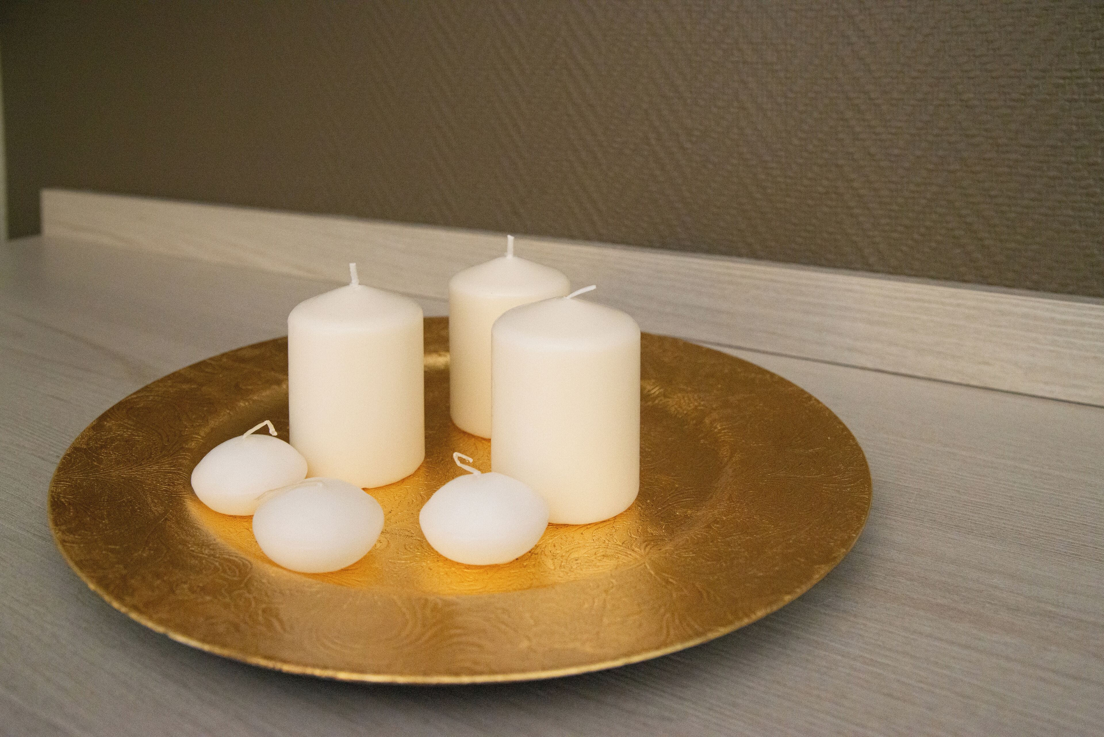 Una mesa con un atril dorado que sostiene velas blancas.