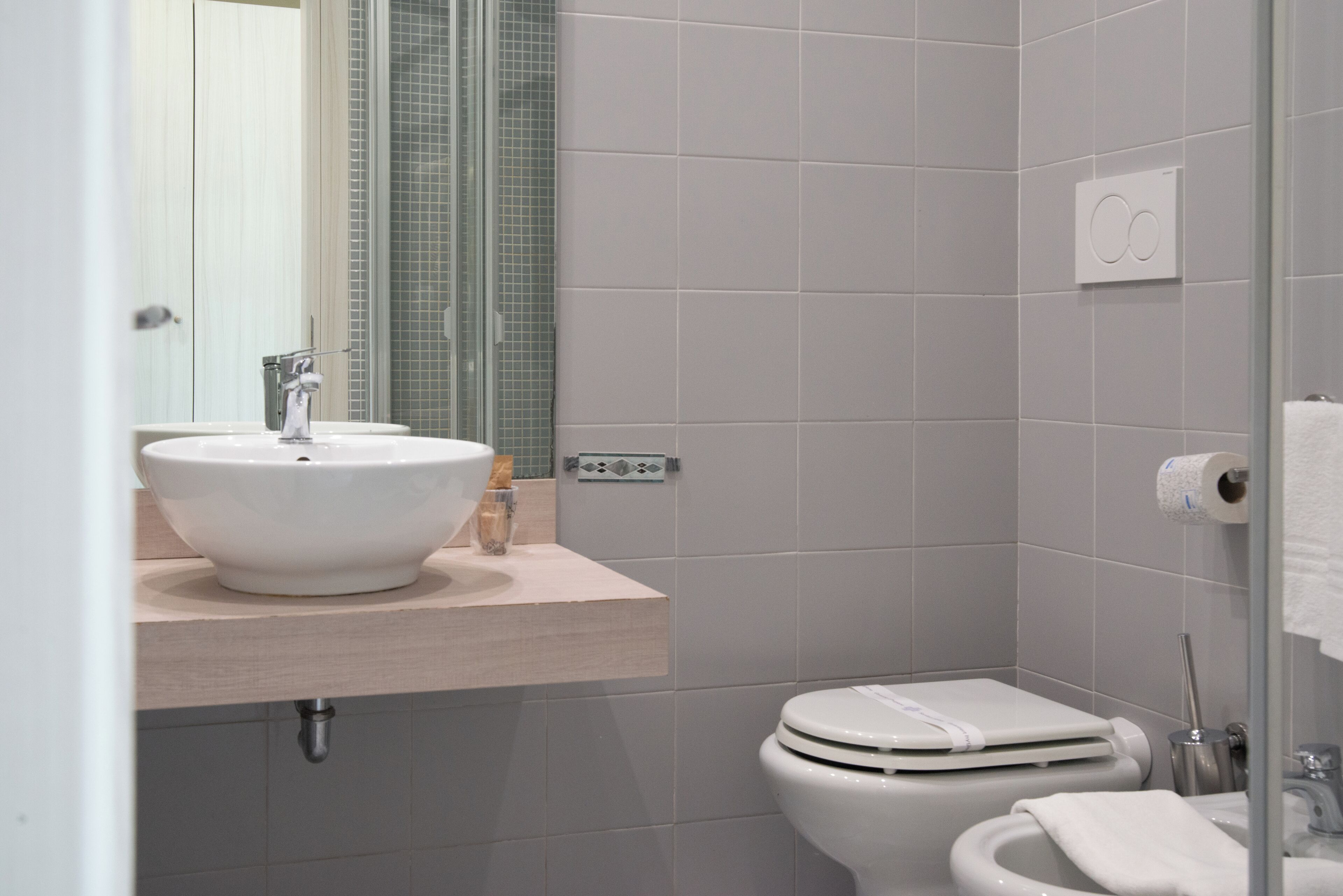Un bagno moderno con lavandino, specchio e servizi igienici bianchi.