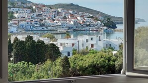 A coastal town with white buildings, a harbor, and a hillside in the background. - Villa Arni (Andros)