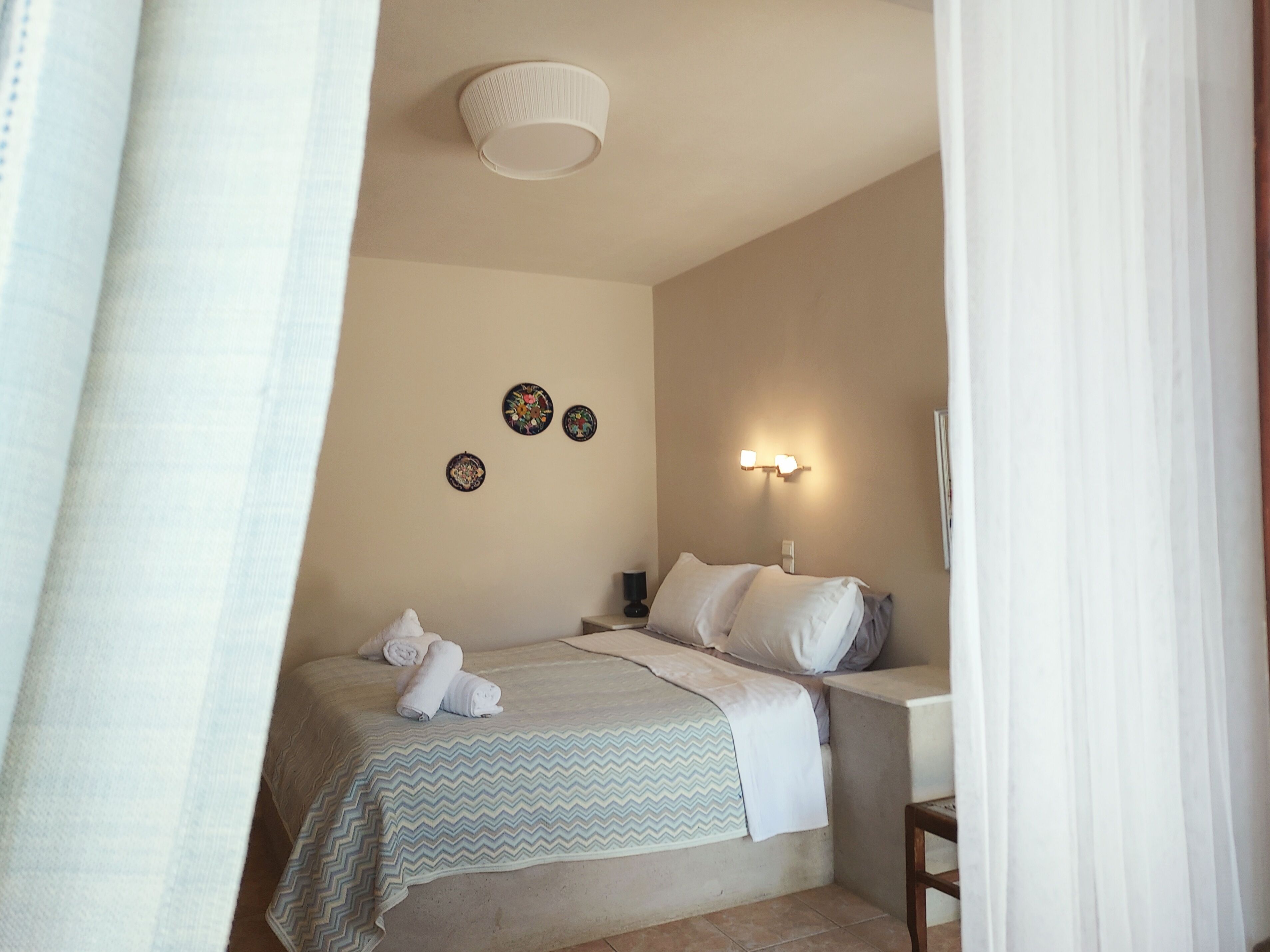 Un dormitorio con cama, mesita de noche, lámpara de pared y placas decorativas.