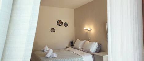 Un dormitorio con cama, mesita de noche, lámpara de pared y placas decorativas.