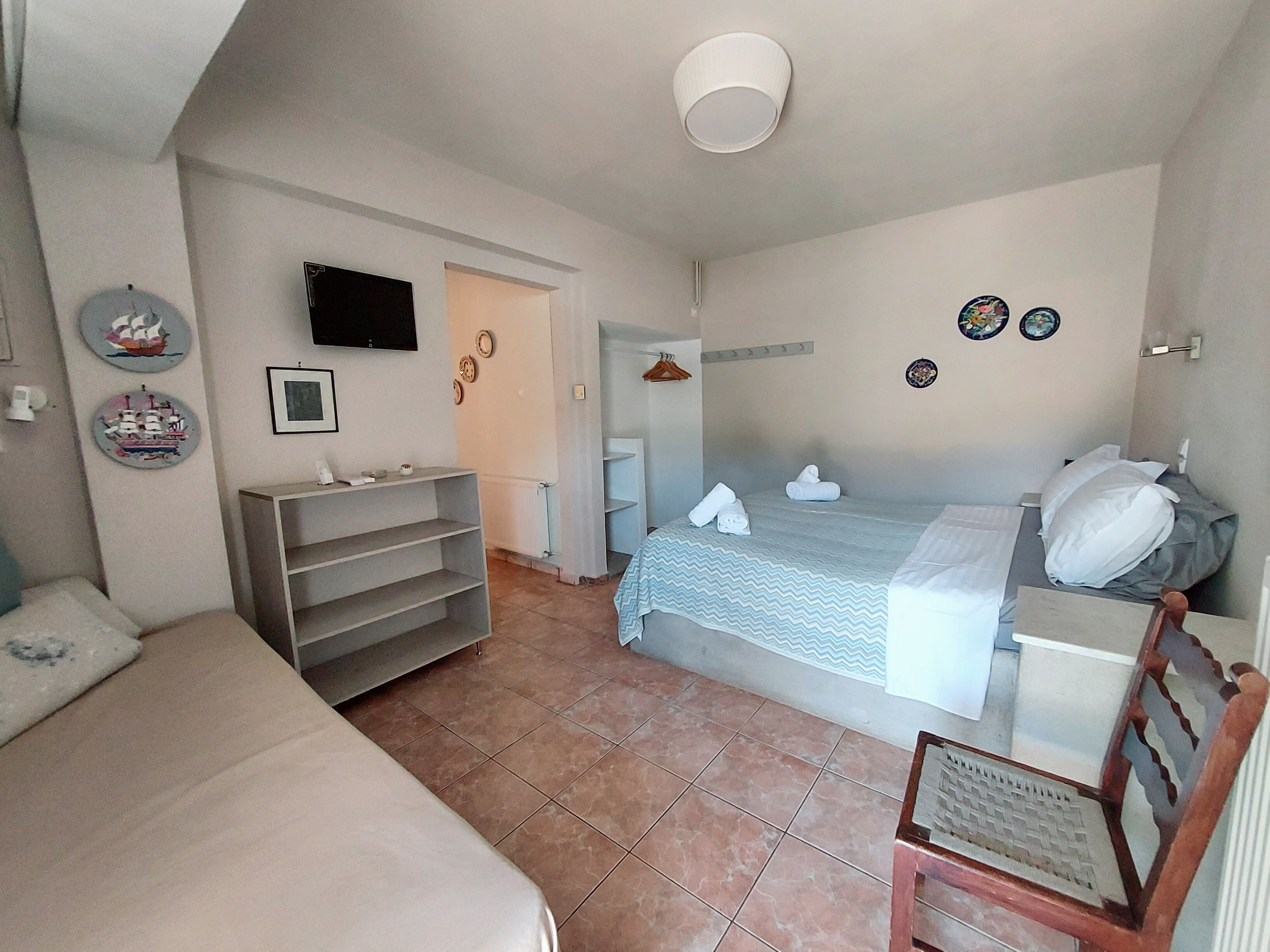 A hotel room with a bed, a desk, a chair, a TV, and a bathroom door.