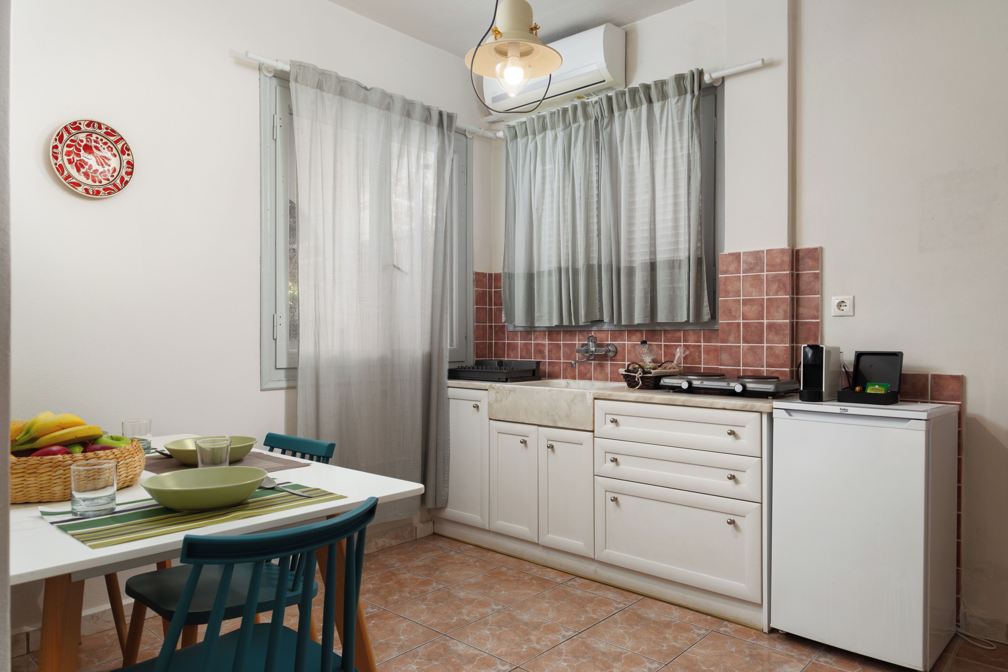 Une cuisine compacte avec des meubles blancs, un petit plan de travail et un coin repas comprenant une table et des chaises.
