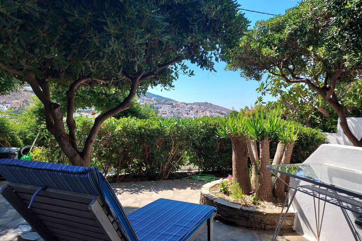 Un patio con dos sillones, suelo de piedra y vistas a un pueblo en la ladera.