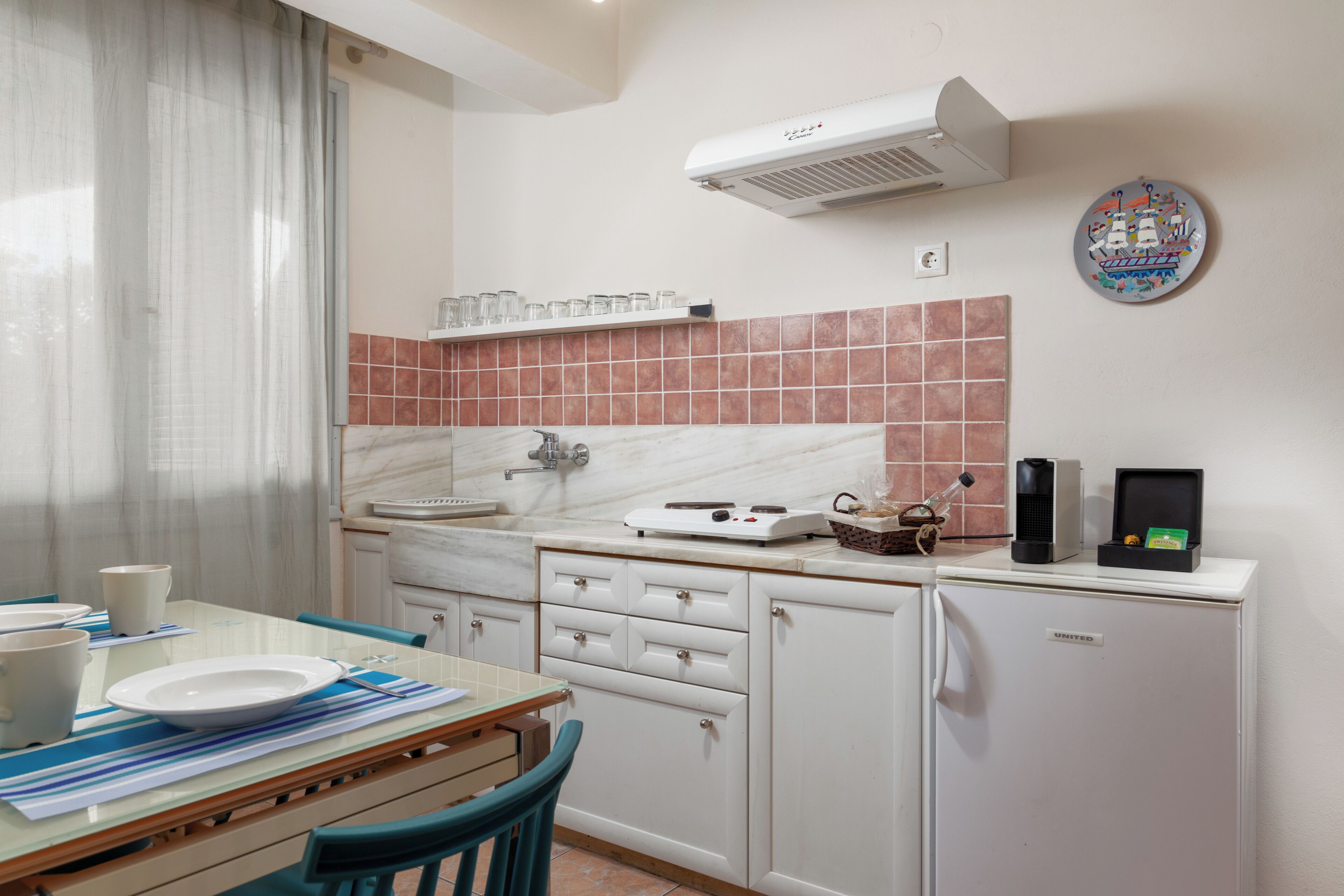 Cocina compacta con comedor, que incluye refrigerador, microondas, cafetera y un lavamanos pequeño.