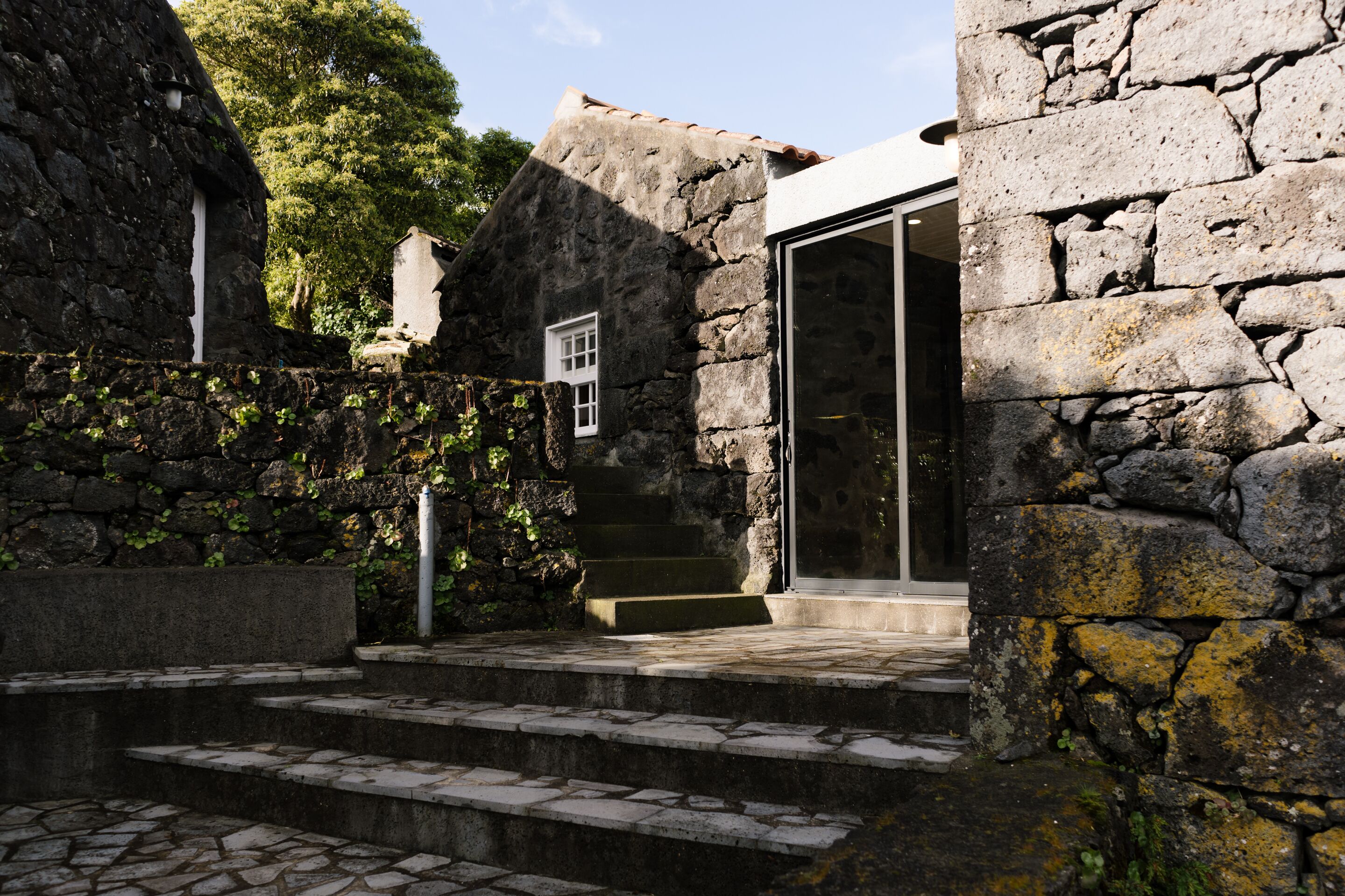 A stone building with a glass door entrance, steps leading up to it, and a small window.