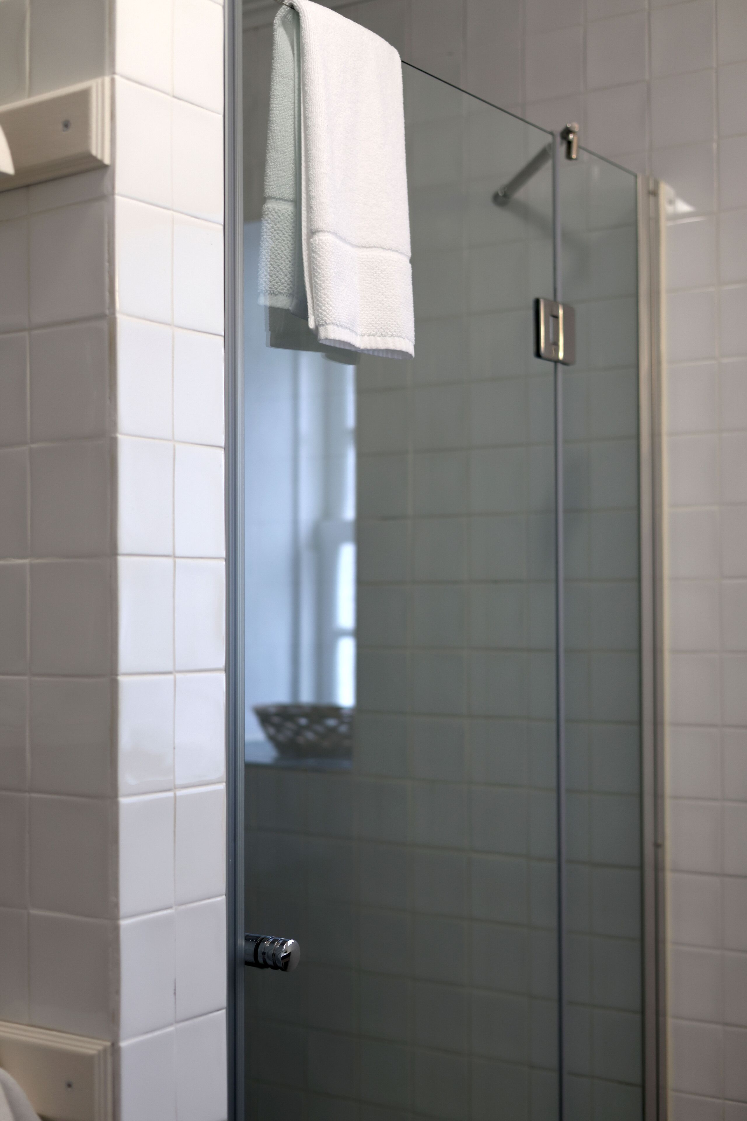A glass-enclosed shower stall with a white towel hanging on the door handle.