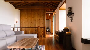 A cozy living room with a sofa, a wooden coffee table, and a striped rug. - Adegas do Pico (Sao Roque do Pico)