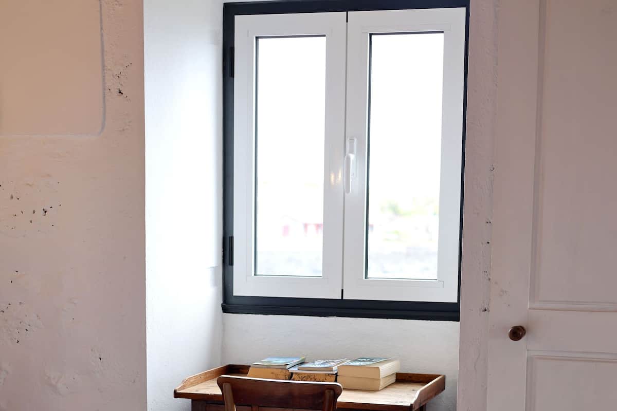 A room with a bed, a desk with a chair, and a window.