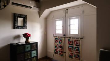 A room with a dresser, a mirror, and a quilt hanging on the wall.