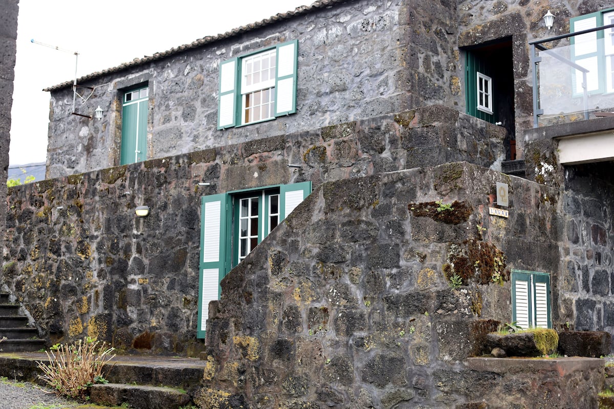 A stone building with green shutters and a sign that reads "LAGAS."