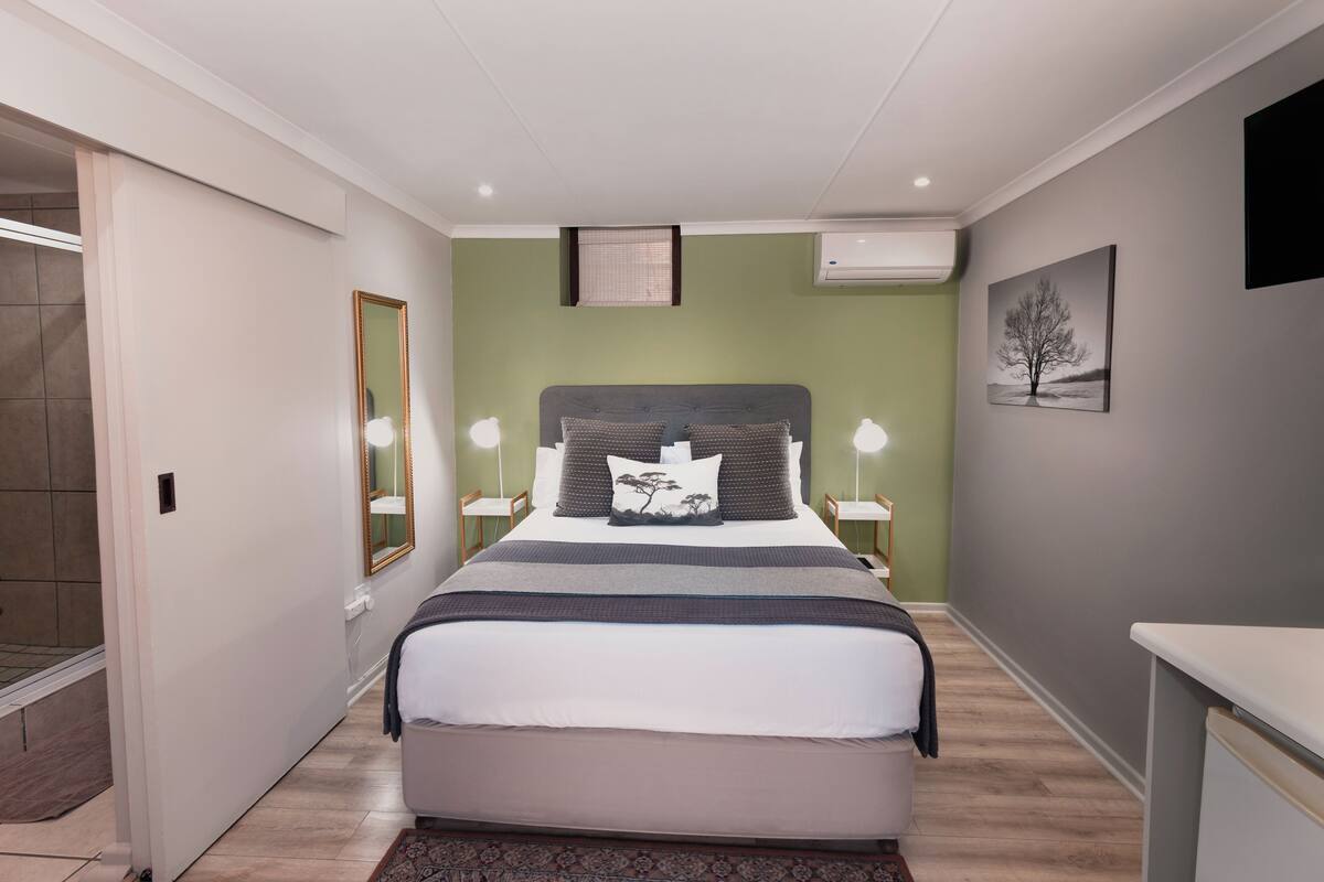 Quarto moderno com uma cama grande, luminárias de cabeceira, um espelho e uma mesinha.