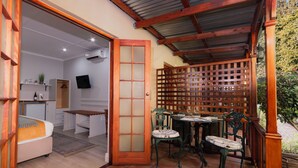 A cozy room with a bed, a small table, and chairs. There is a wooden partition and a TV mounted on the wall.