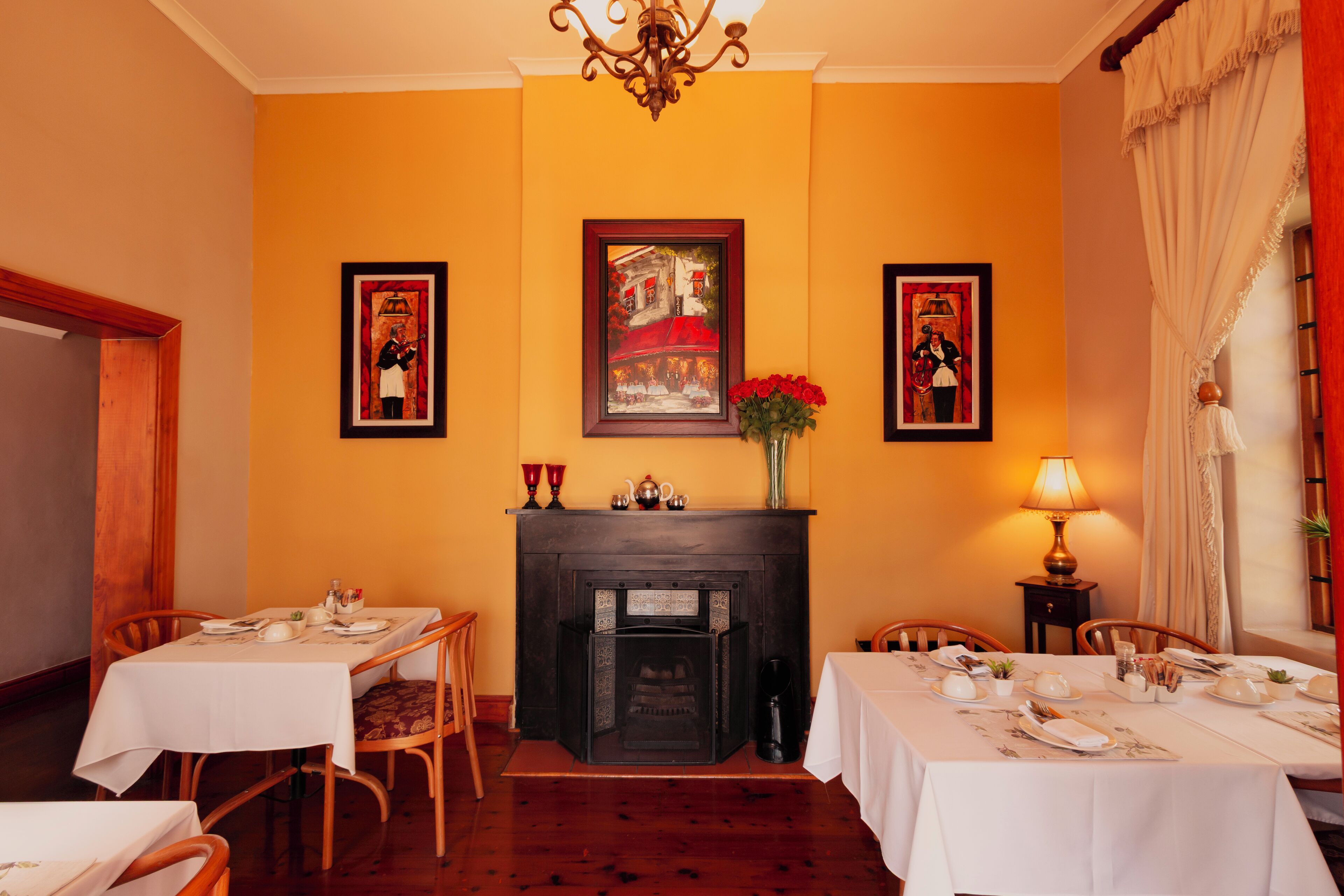 A dining room with a fireplace, framed artwork, and a table set for a meal.