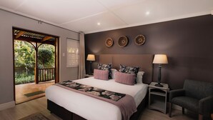 A bedroom with a large bed, two bedside tables with lamps, a chair, and a view of the outdoors through a sliding door.