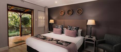 A bedroom with a large bed, two bedside tables with lamps, a chair, and a view of the outdoors through a sliding door.