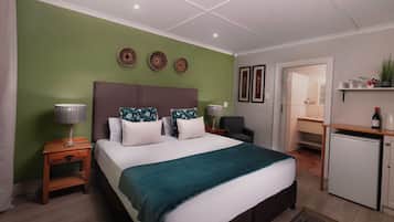 A neatly arranged bedroom with a bed, bedside tables, a desk, and a refrigerator.