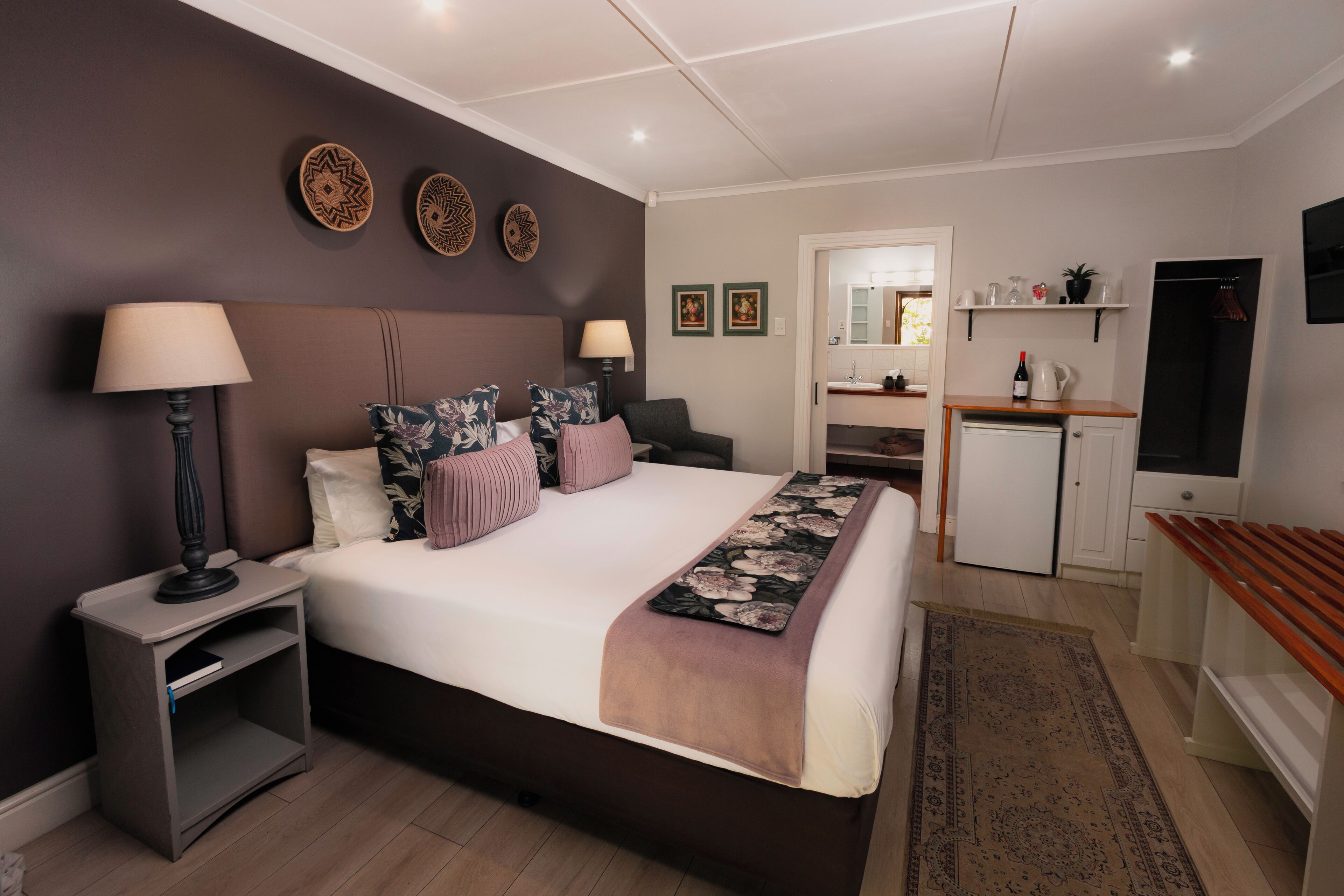 A bedroom with a bed, bedside tables, a desk, a mirror, and a wardrobe.