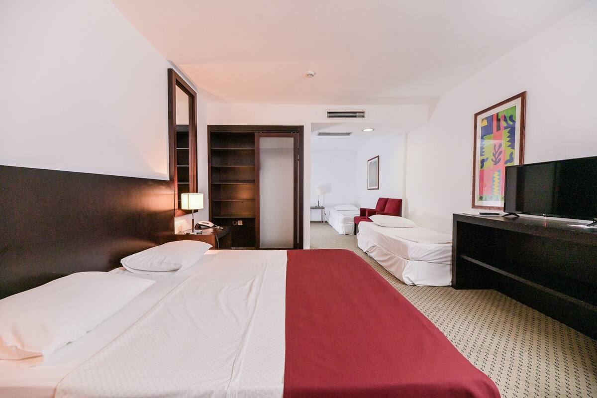 Une chambre d’hôtel équipée d’un lit, d’une télévision, d’un bureau, d’une chaise et d’une armoire.