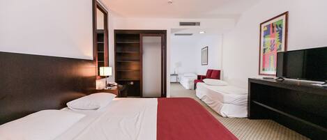 A hotel room with a bed, a TV, a desk, a chair, and a wardrobe.