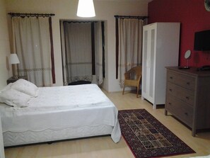 Ein Schlafzimmer mit einem Bett, einem Schminktisch, einem Stuhl, einem Kleiderschrank und einem gemusterten Teppich.