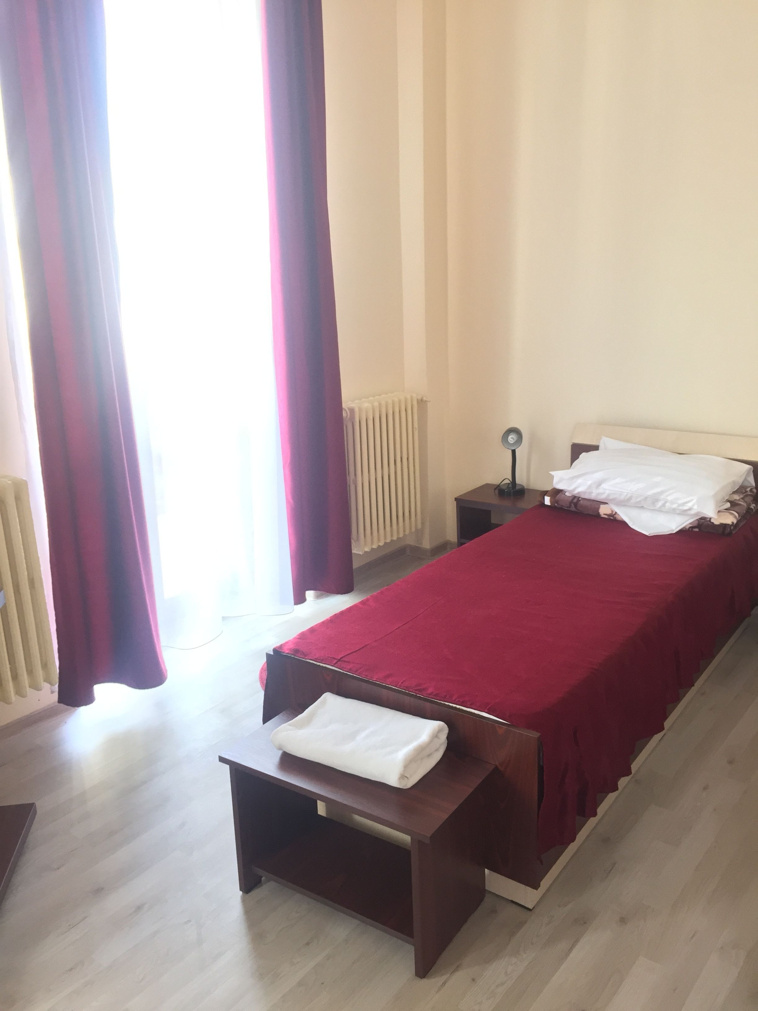 A bedroom with a bed, a bedside table, a lamp, and a radiator.