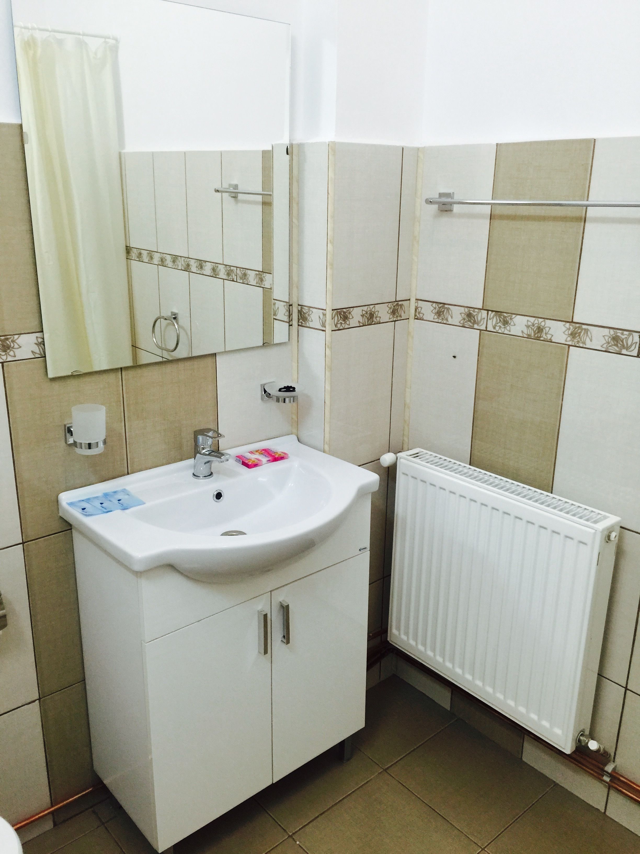 A bathroom with a white sink, mirror, and radiator.