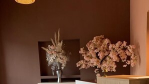 Un espace d’accueil avec un comptoir en bois portant l’inscription « RÉCEPTION », une cheminée et deux compositions florales.