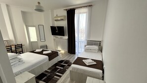Une chambre d’hôtel avec deux lits, une télévision, un bureau et une fenêtre avec des rideaux.