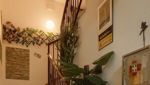 Una escalera con barandilla de madera, un cartel en la pared y una planta en maceta.