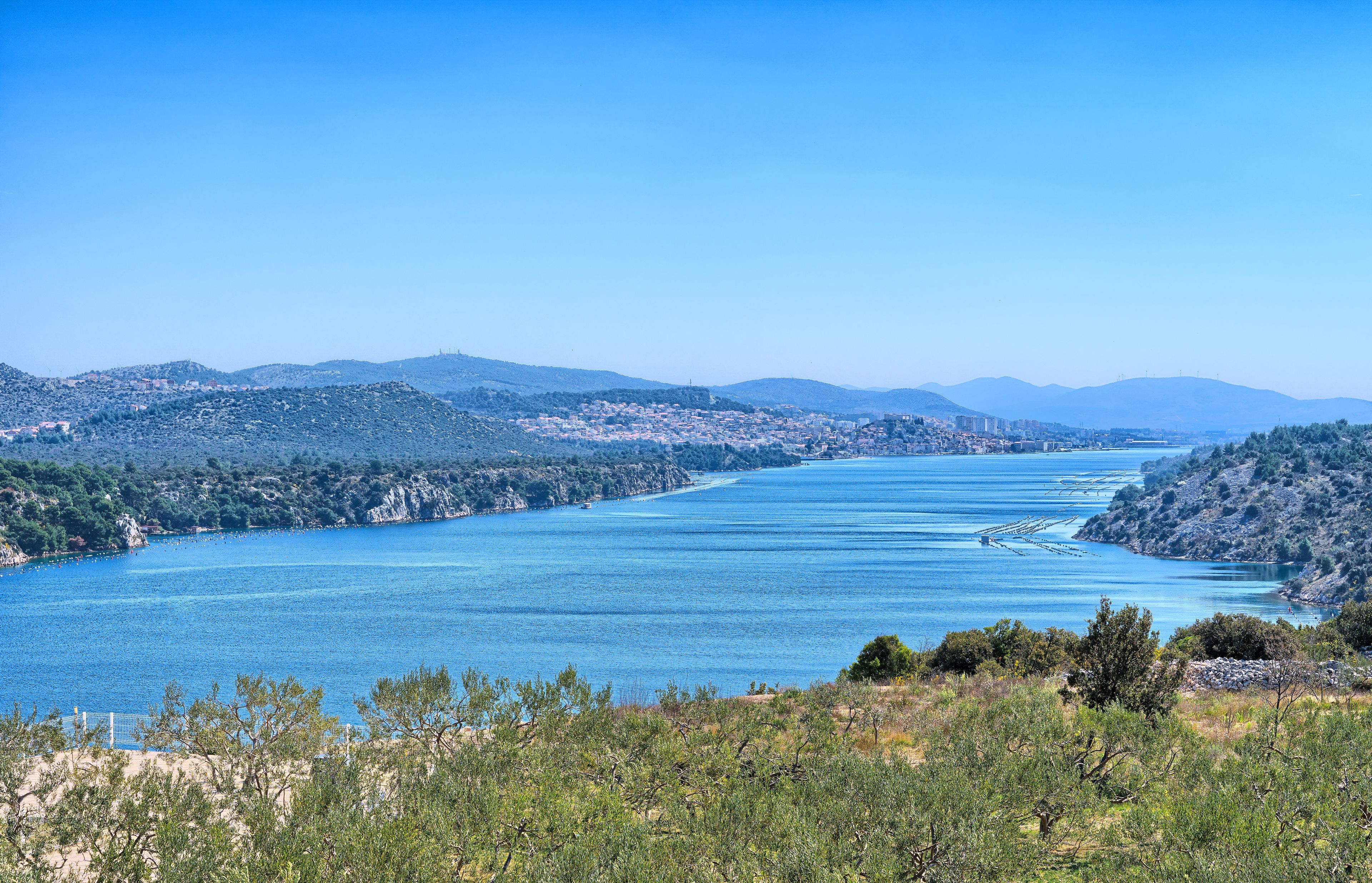 Un paisaje costero con un río ancho, colinas y vegetación escasa.